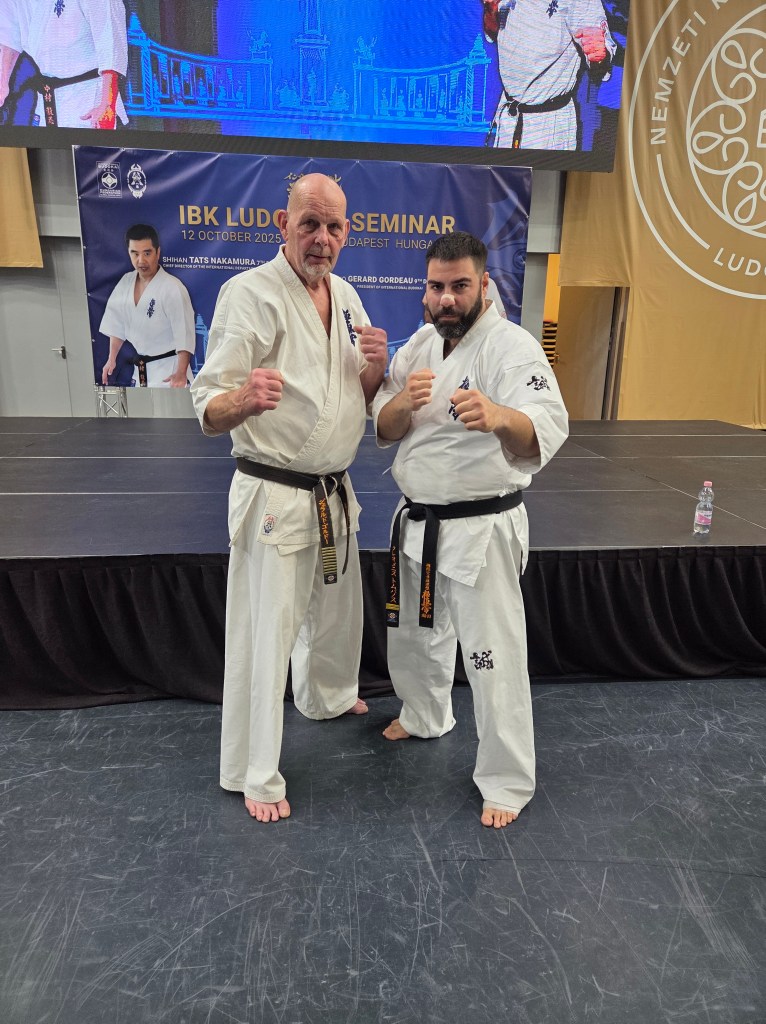A black belt instructor posing in a fighting stance with Kancho Gerard Gordeau (9th Dan) at the IBK Ludovika Seminar.