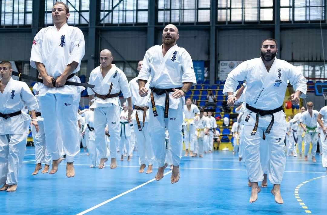 Several male karate practitioners mid-air, performing a high vertical jump during a conditioning drill at Senshi Camp.